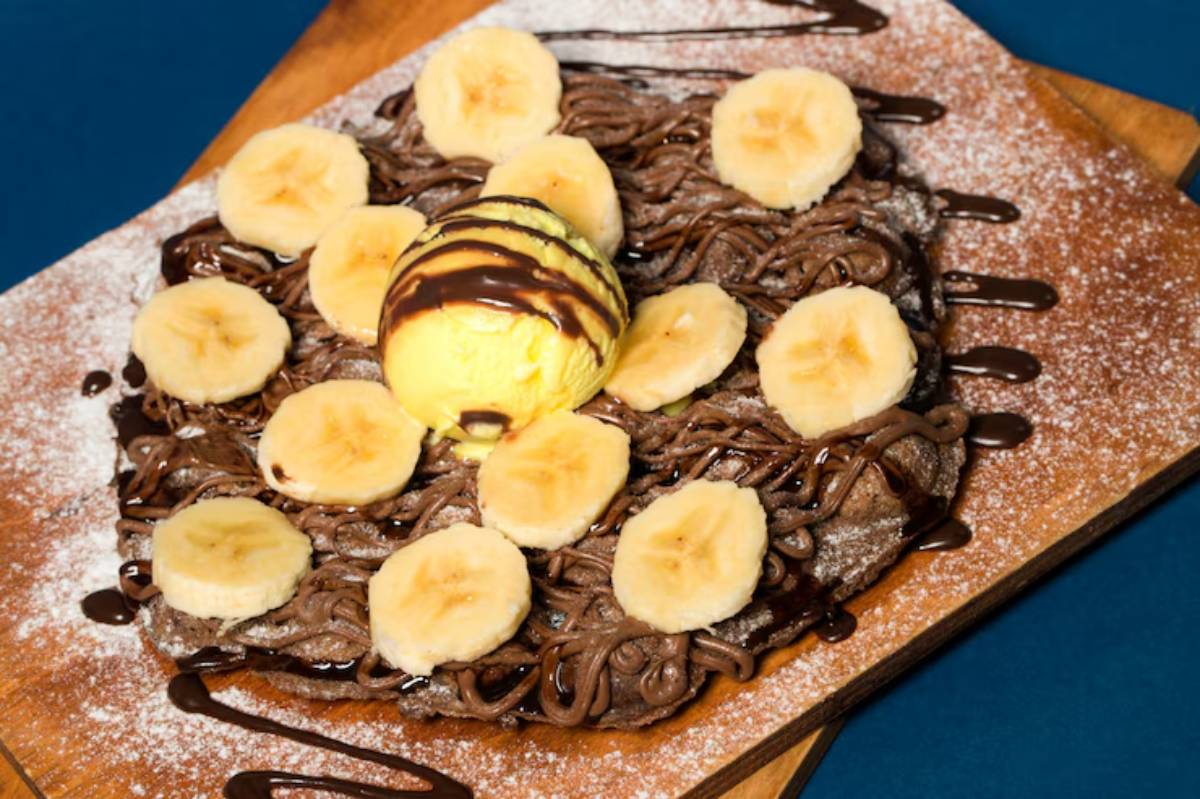 A chocolate dessert topped with banana slices and a scoop of vanilla ice cream, drizzled with chocolate sauce on a wooden platter.
