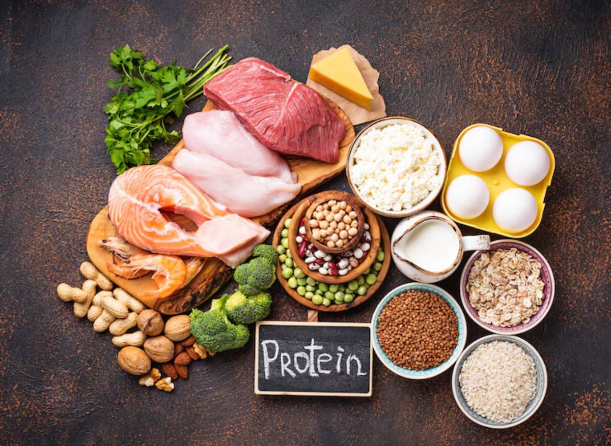 A variety of protein-rich foods including meats, fish, dairy, legumes, nuts, and grains, arranged on a dark background.