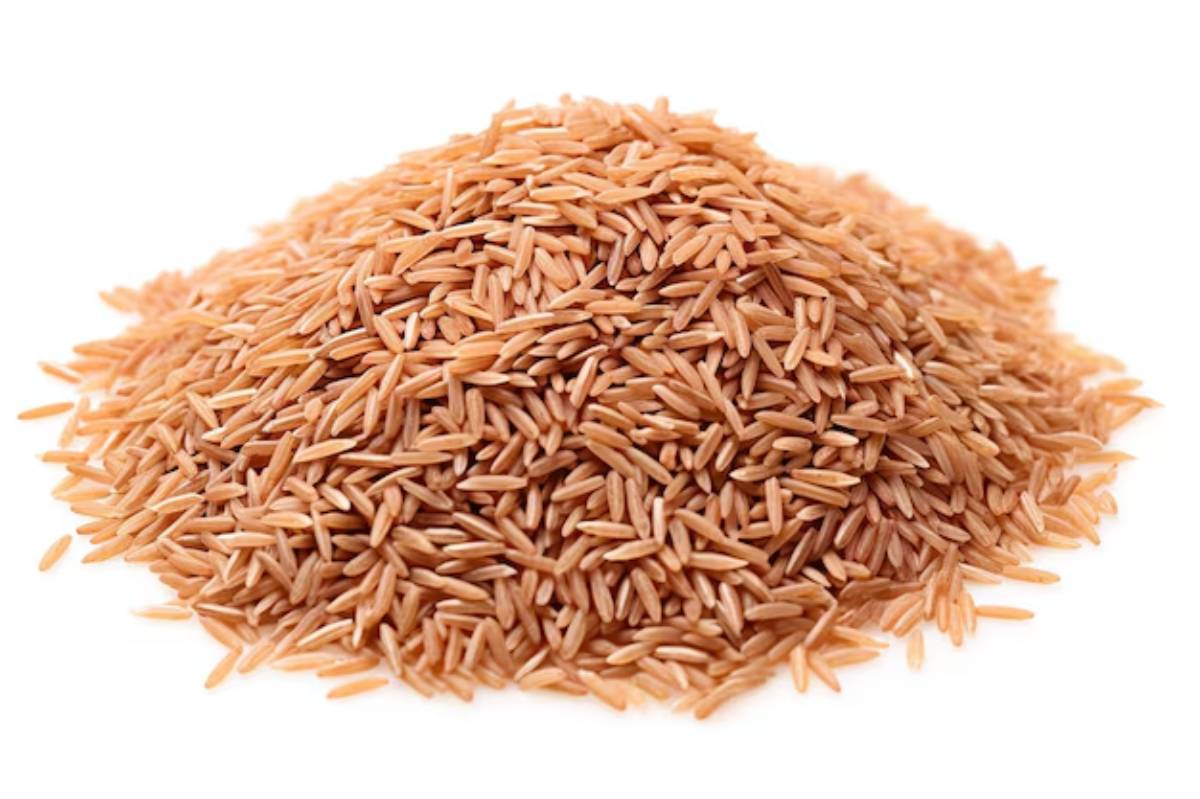 A mound of light brown uncooked rice grains, showcasing their elongated shape and natural texture against a white background.